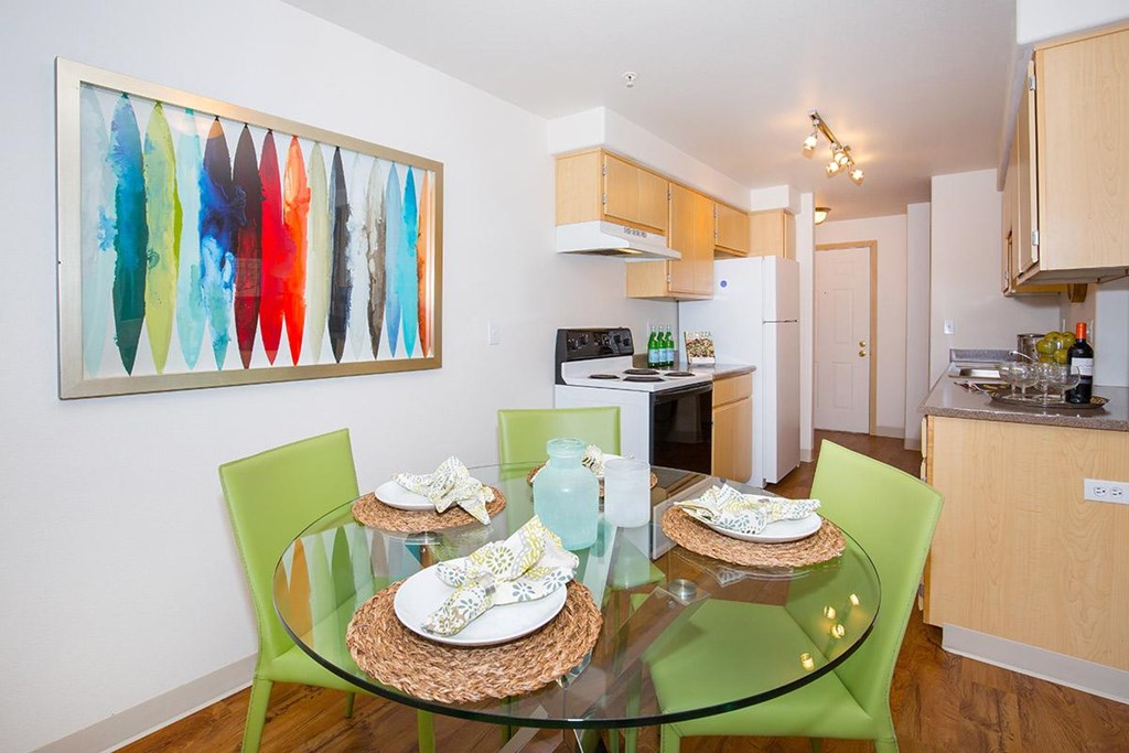 a dining room table with green chairs and a kitchen